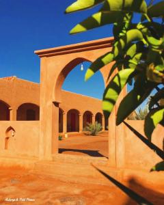 a building with an arch in the middle of a desert at Hotel Riad Le Petit Prince in Merzouga