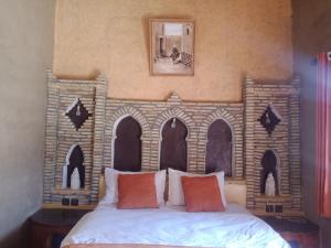 a bedroom with a bed with a brick wall at Hotel Riad Le Petit Prince in Merzouga