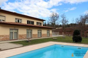 a house with a swimming pool in front of a house at Outeiro do Moinho - Rooms & Bungalows in Campo do Gerês