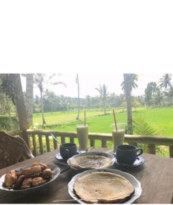 una mesa de madera cubierta con platos de comida y bebida en Eltari Homestay, en Tetebatu