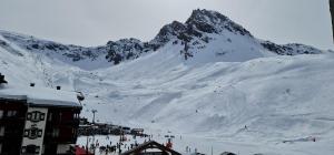 a group of people skiing down a snow covered mountain at Tignes rond point des pistes vue panoramique au soleil in Tignes