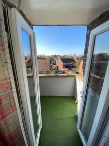 a balcony with green flooring and two large windows at Bright, Spacious, modern Interior Decor 2 bedrooms Apartment with amazing views in London