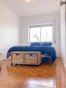 Un dormitorio con una cama con una manta azul y una ventana. en Beach Lovers Surf House - Aveiro - Praia da Barra, en Praia da Barra