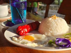 une assiette de nourriture avec un œuf et du riz sur une table dans l'établissement Camp Paraiso Resort, à Salabusob