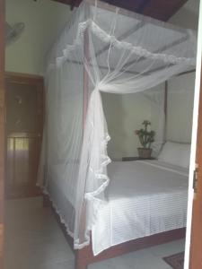 a bedroom with a white canopy bed with a potted plant at Sigiriya Nature View home Stay in Sigiriya