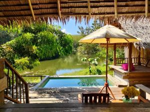宋卡的住宿－塔省帕拉度假村，一个带遮阳伞和桌椅的游泳池