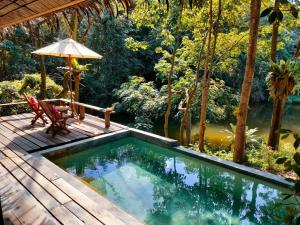 una piscina en una terraza con una silla y una sombrilla en Thap Pala Cottage, en Songkhla