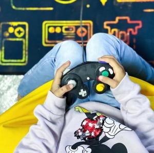 a person laying on a bed holding a video game controller at Hideout Farmhouse - By Seven Elements in Ras al Khaimah