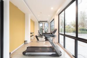 a gym with a treadmill and large windows at The Proud Exclusive Hotel-SHA Plus in Nakhon Pathom