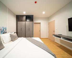 a bedroom with a large white bed and a television at College Haus Rangnam in Bangkok