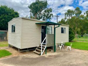 een tiny house met een veranda en een tafel bij Cootamundra Caravan Park in Cootamundra