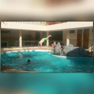 a person jumping in a swimming pool at Neradom Hotel in Tema