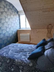 1 dormitorio con cama con sábanas azules y ventana en Grand T2 proche canal de Nantes à Brest. en Châteauneuf-du-Faou