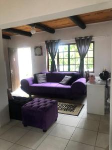 a purple couch in a living room with windows at Villa Jullienne - A Home Away From Home - Unit 8 in Nelspruit