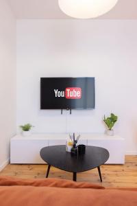 Una sala de estar con un televisor en una pared blanca. en Emeraude, T2 design tout équipé Châteaucreux-Gare, en Saint-Étienne