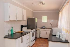 a kitchen with a stove and a refrigerator at Oakdene Cottage in Roodepoort