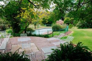 a group of chairs sitting on a brick patio with a pool at Oakdene Cottage in Roodepoort