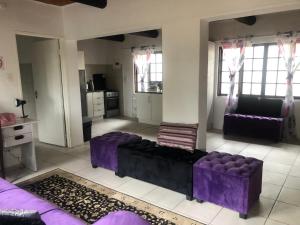 a large living room with purple furniture and windows at Villa Jullienne - A Home Away From Home - Unit 8 in Nelspruit