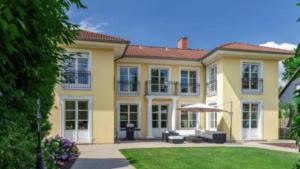 una gran casa amarilla con un paraguas en el patio en Villa am Steinhuder Meer Superior DZ-Azur- mit kl Pantry Küche, Garten, WLAN, en Steinhude