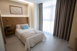 ein Hotelzimmer mit einem Bett und einem großen Fenster in der Unterkunft Hotel Boutique O Náutico Laxe in Laxe