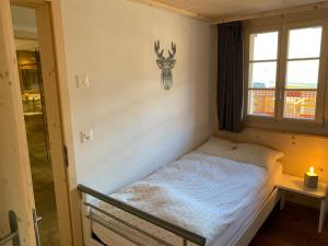 Dormitorio con cama con cabeza de ciervo en la pared en Büehl Lenk, en Lenk