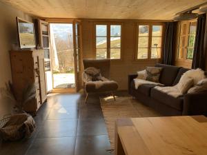 een woonkamer met een bank, stoelen en ramen bij Büehl Lenk in Lenk