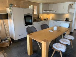 uma cozinha com uma mesa de madeira e armários brancos em Büehl Lenk em Lenk