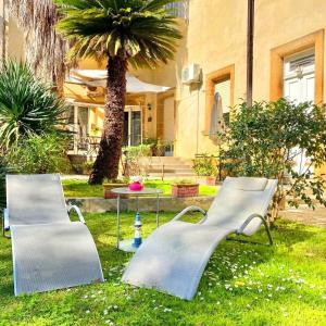 dwie ławki siedzące w trawie blisko palmy w obiekcie Aedes B&B Il Giardino dei Sogni w mieście Lecce
