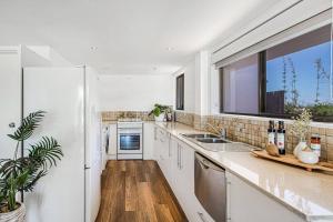 cocina con electrodomésticos blancos y ventana grande en Lovely 2bd Unit, Patio and views. Best weekly rate, en Alexandra Headland