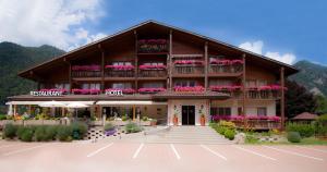 a building with flowers on the balconies and a parking lot at SALZANO Hotel - Spa - Restaurant in Interlaken