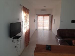 a living room with a television and a couch at Appartement familial spacieux avec climatisation in Ziguinchor