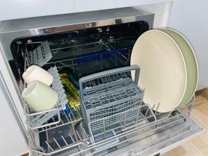 an open dishwasher with a plate and dishes in it at Casa das Férias in Lisbon