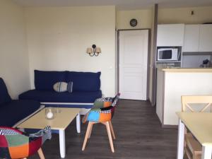 uma sala de estar com um sofá azul e uma mesa em Résidence des sables blancs em Douarnenez