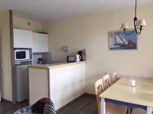 a small kitchen with a table and a table and chairs at Les Terrasses des Sables Blancs in Douarnenez +8 photos