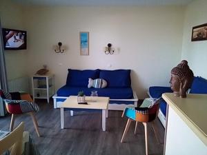 uma sala de estar com um sofá azul e uma mesa em Résidence des sables blancs em Douarnenez