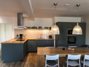 cocina con armarios verdes y mesa de madera en Naar Zee op Ameland en Buren