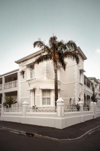 a white house with a palm tree in front of it at NOAH House in Cape Town