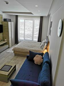 a bedroom with a blue couch in front of a bed at Apartman Šilja L22 Milmari Kopaonik in Kopaonik +65 photos
