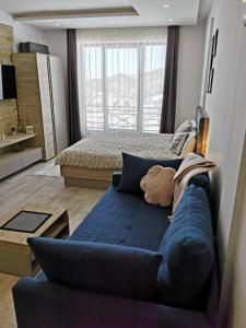 コパオニクにあるApartman Šilja L22 Milmari Kopaonikの青いソファとベッドのあるリビングルーム
