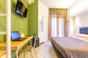 a bedroom with a bed and a desk with a laptop at Hotel La Nidiola in Riccione