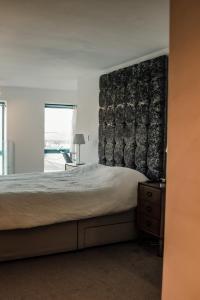 a bedroom with a large bed with a black headboard at Apartments-DealHouse in Huddersfield