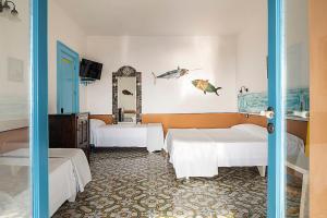 a bedroom with two beds and a mirror at Hotel Mamma Santina in Santa Marina Salina