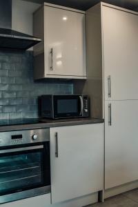 a kitchen with white cabinets and a microwave at Apartments-DealHouse in Huddersfield