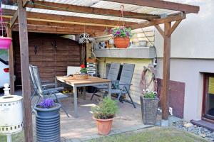 a patio with a table and chairs and a pergola at Ferienwohnungen an der Baaber Heide in Baabe