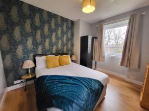 a bedroom with a bed with blue sheets and a window at 4 Bedroom Apts at Sensational Stay Serviced Accommodation Aberdeen- Powis Crescent in Aberdeen