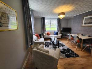 uma sala de estar com um sofá, cadeiras e uma mesa em 4 Bedroom Apts at Sensational Stay Serviced Accommodation Aberdeen- Powis Crescent em Aberdeen