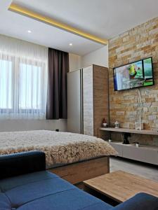 a bedroom with a bed and a tv on a brick wall at Šilja Kopaonik S45 Milmari in Kopaonik