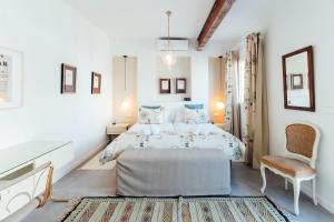 biała sypialnia z łóżkiem i krzesłem w obiekcie MintyStay - La Campana w Sewilli
