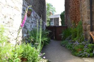 a garden with flowers and a stone wall at Spacious ground floor apartment. No 1A The Stables in Llanfyllin