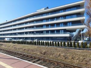 biurowiec z torami kolejowymi przed nim w obiekcie Apartament Luna Baltic Marina Residence w Kołobrzegu